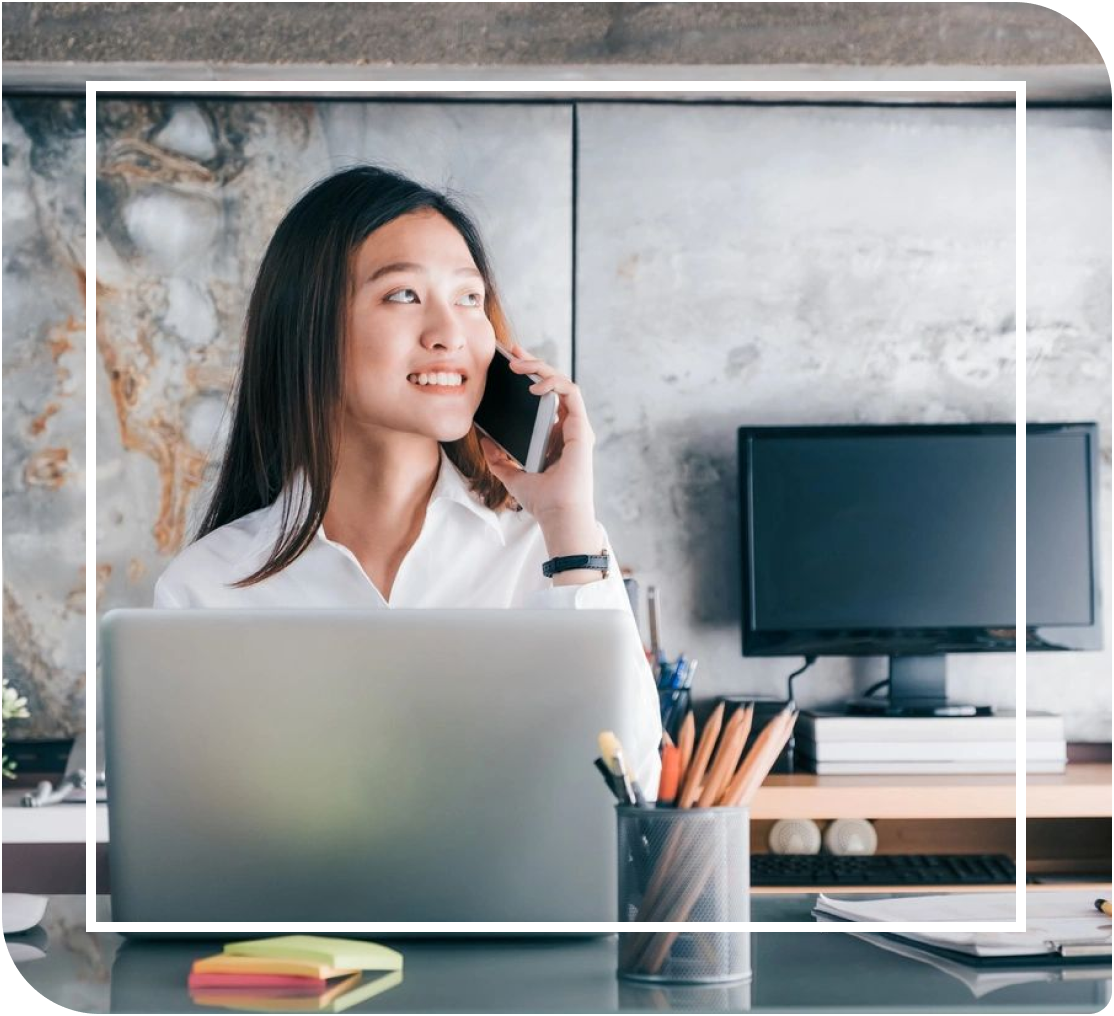 A woman sitting at her desk talking on the phone.