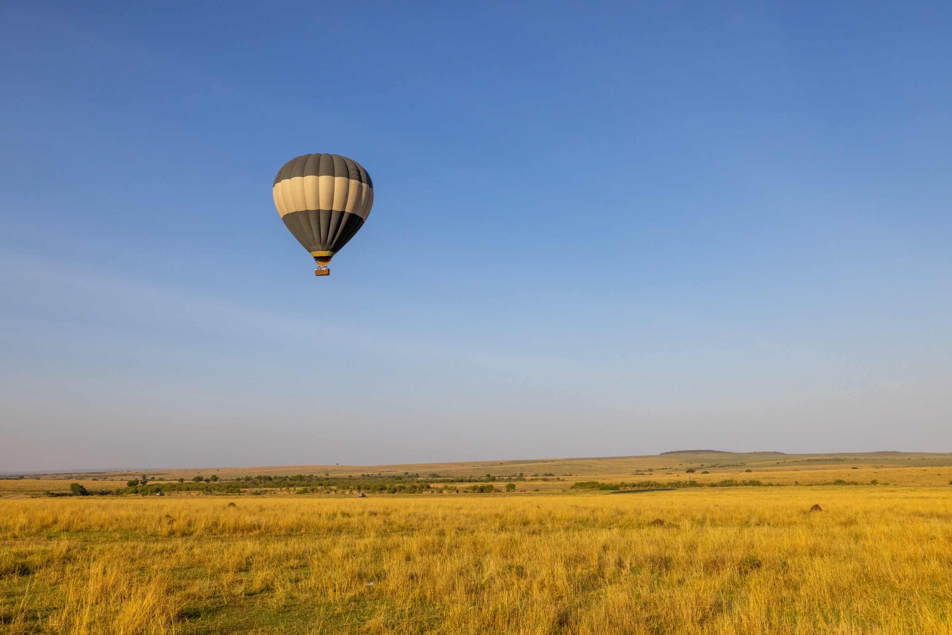 A hot air balloon flying over an open field.