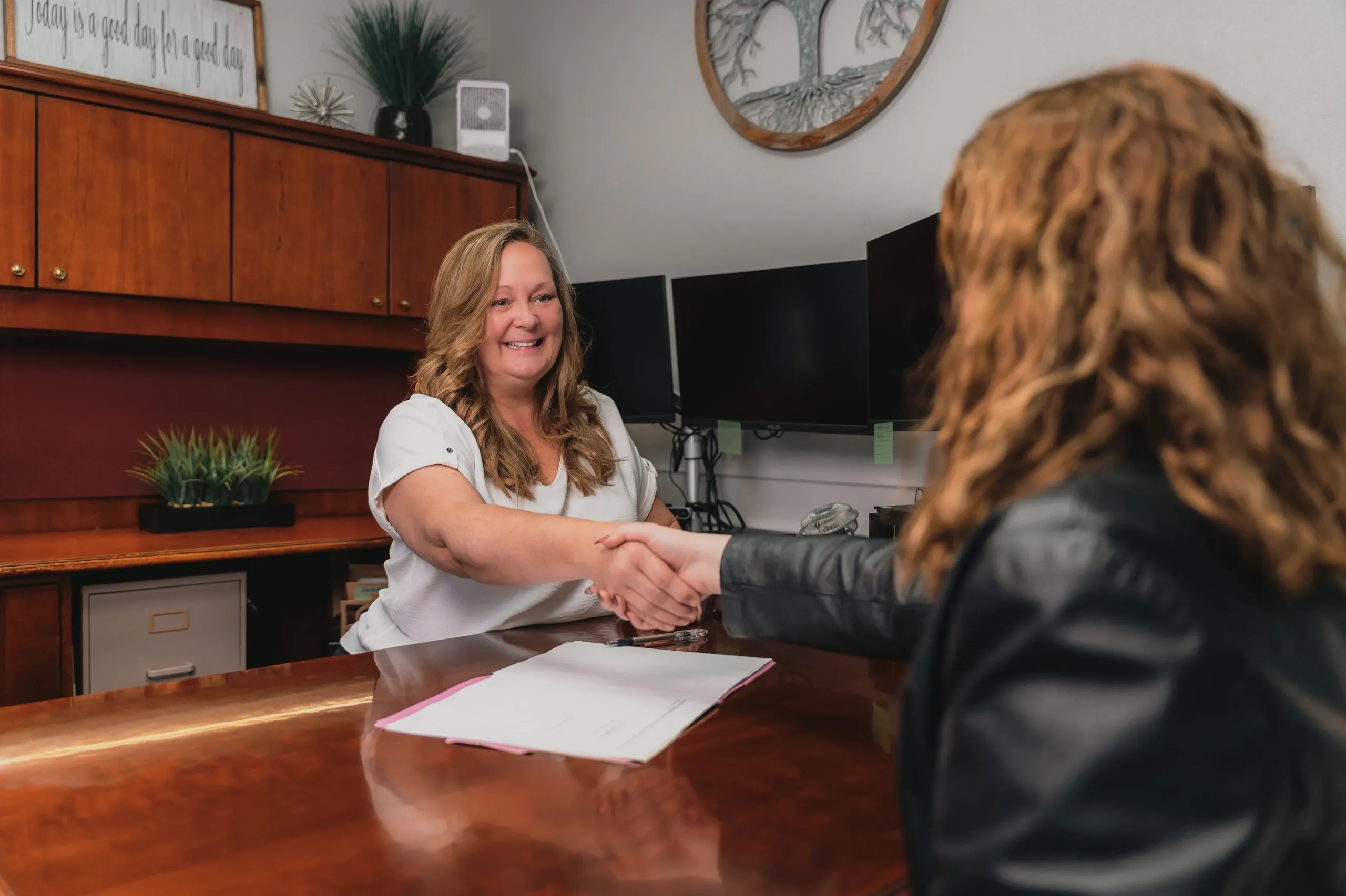 Two women shaking hands in office.