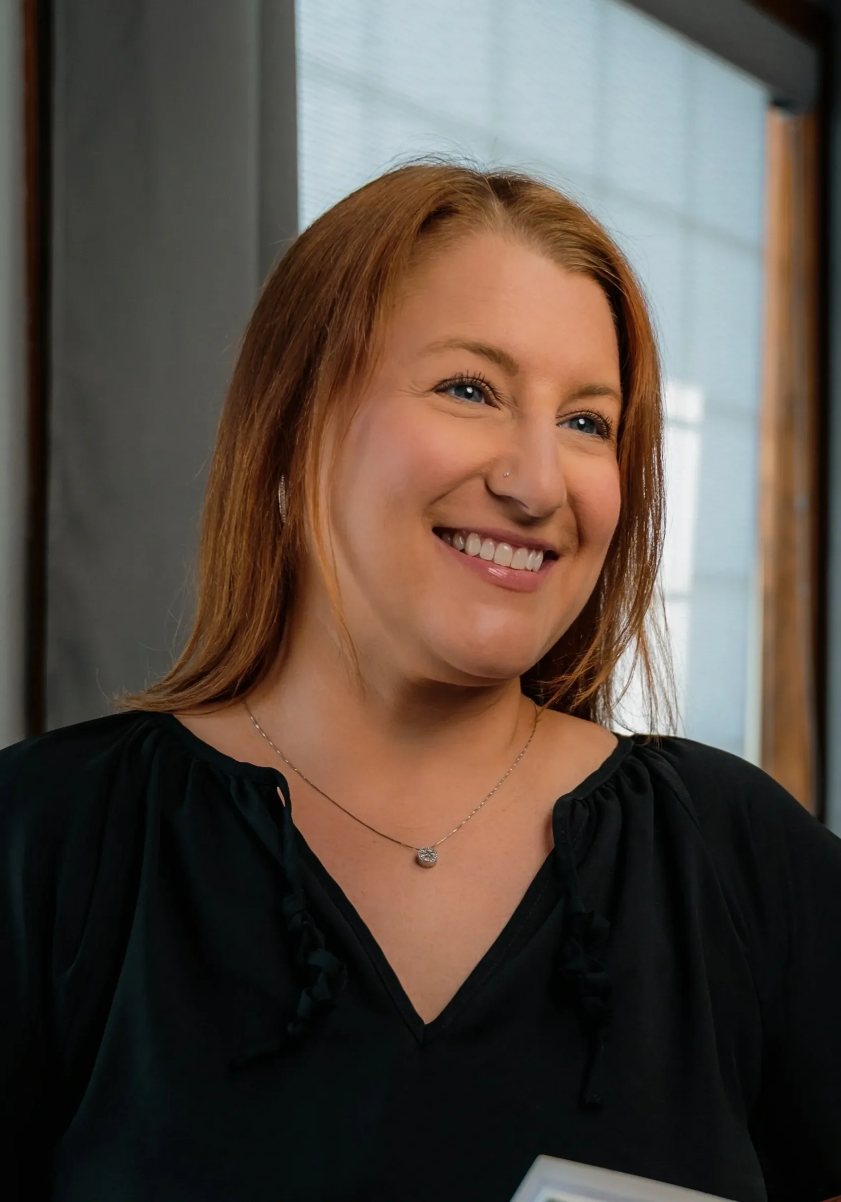 Smiling woman in a black blouse indoors.