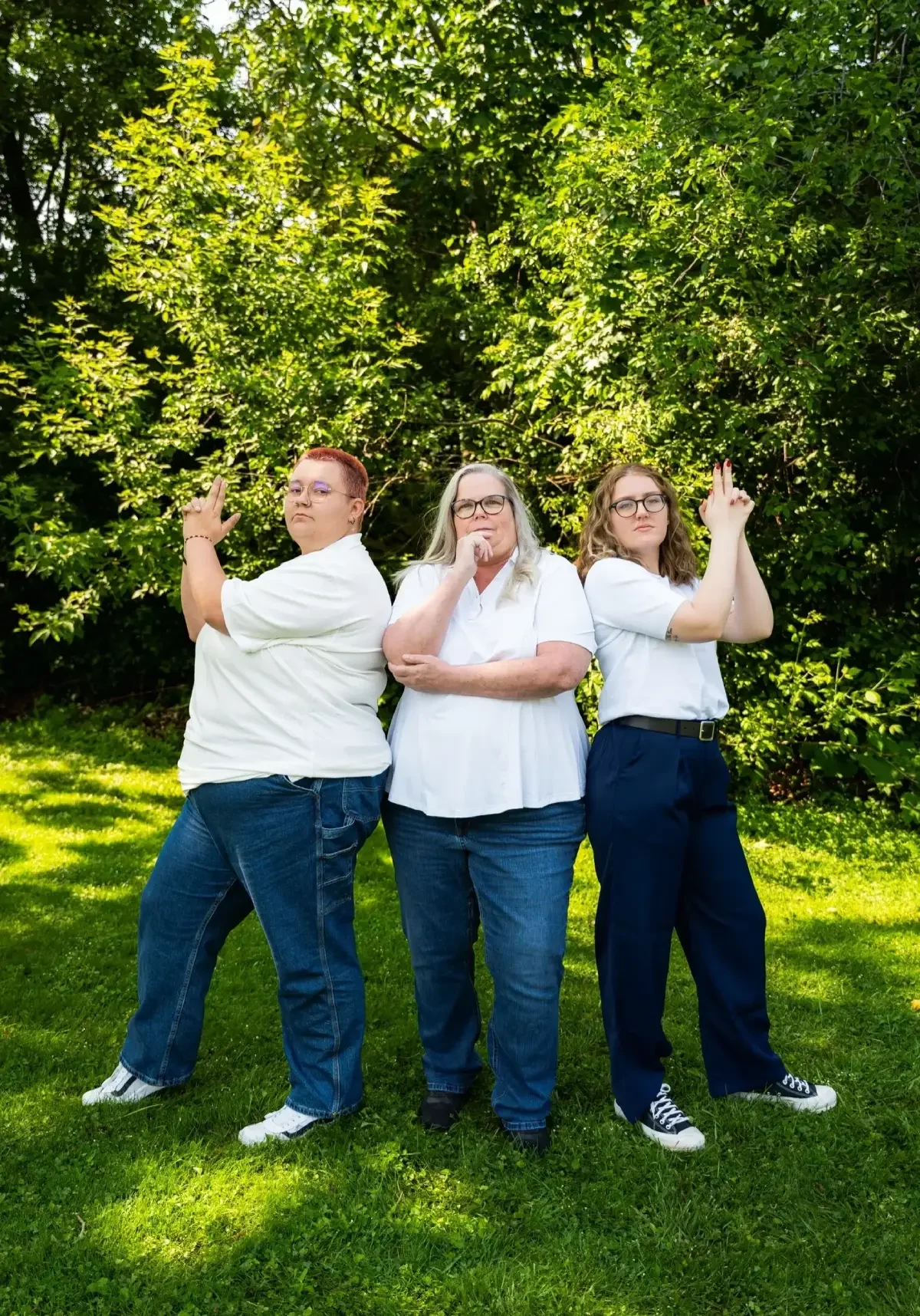 Three people posing like Charlie's Angels outdoors.